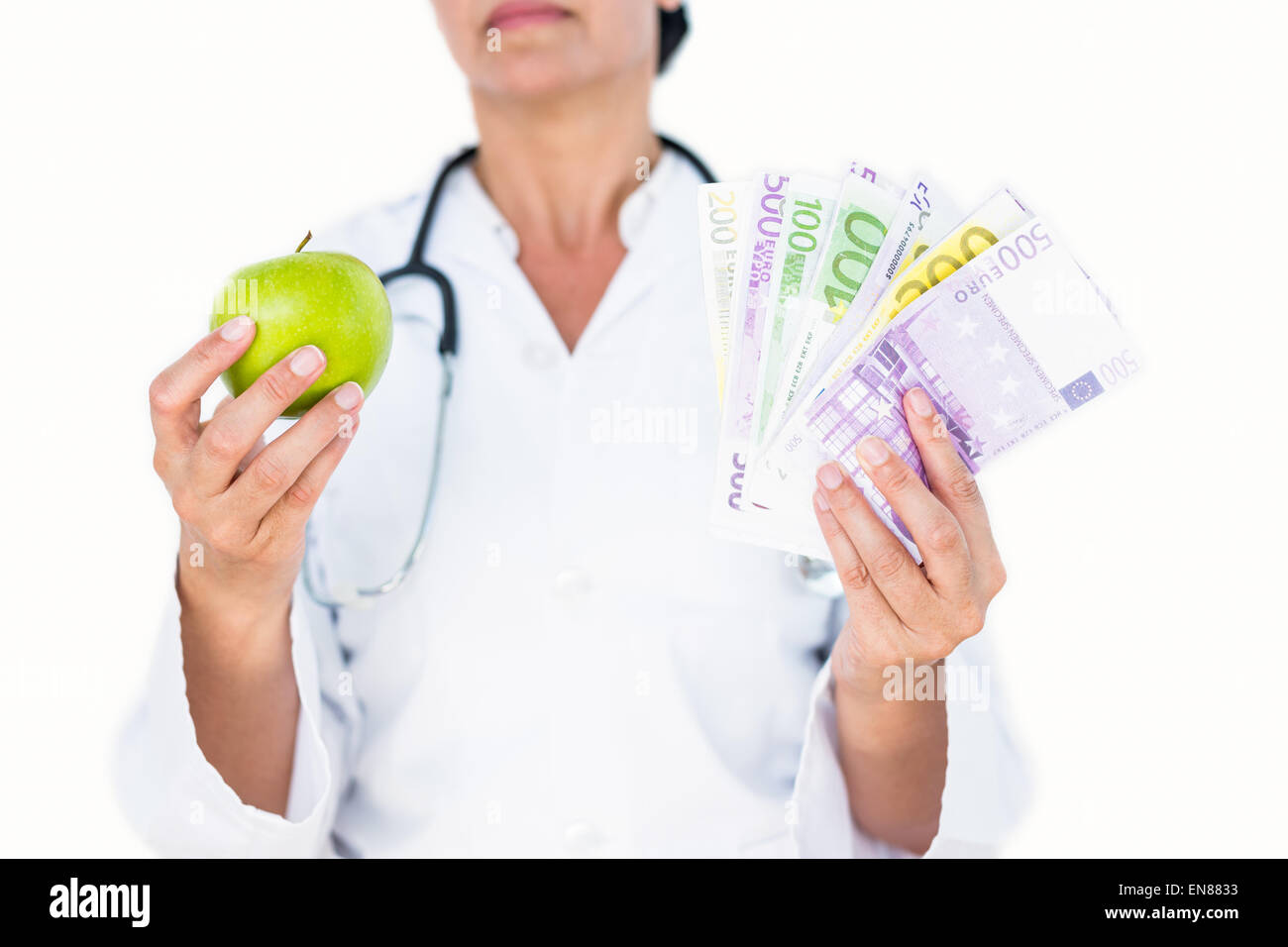 Confident female doctor holding green apple and banknotes Stock Photo
