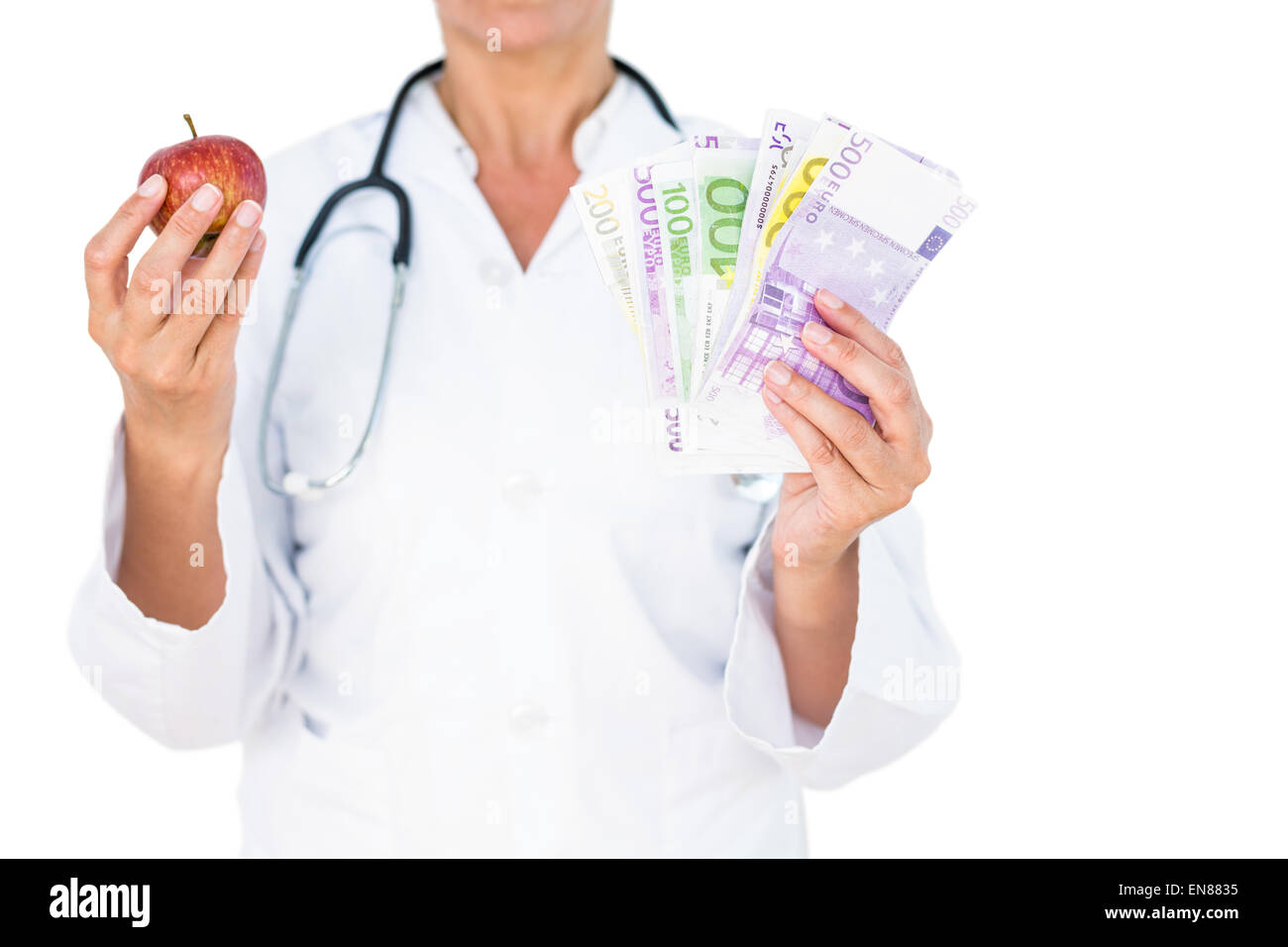 Confident female doctor holding red apple and banknotes Stock Photo