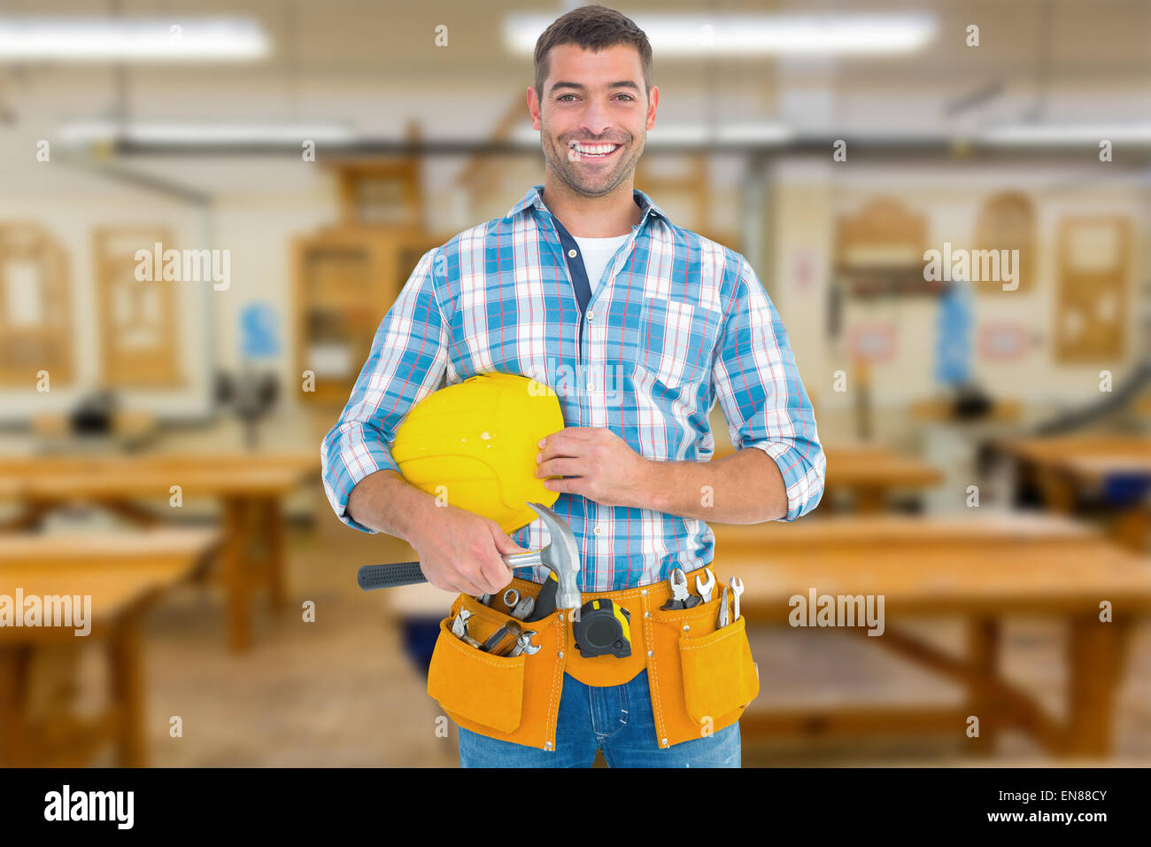 Composite image of smiling handyman holding hardhat and hammer Stock Photo