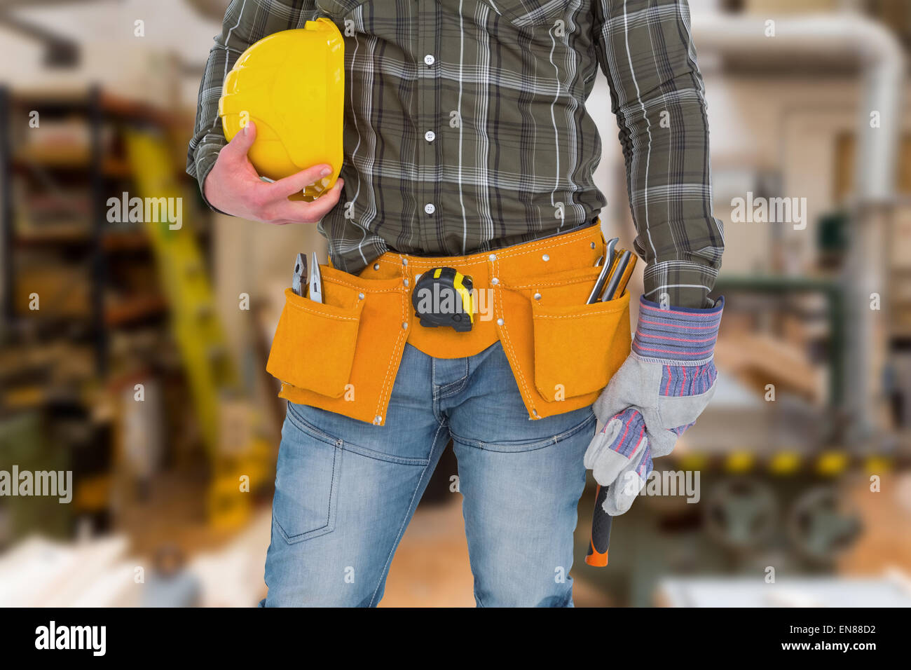 Composite image of manual worker wearing tool belt while holding gloves and helmet Stock Photo