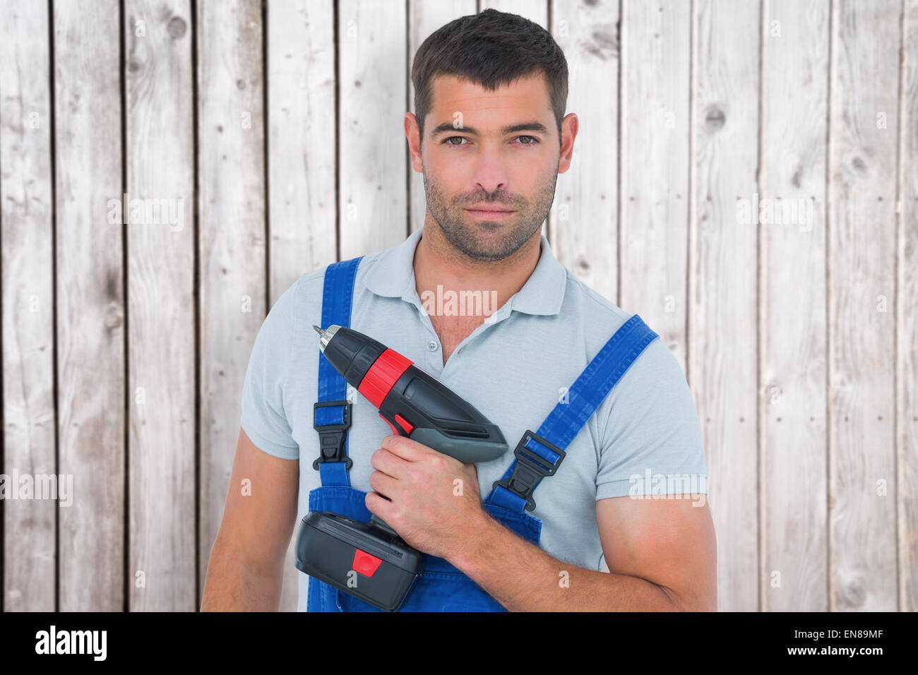 Composite image of portrait of confident carpenter holding power drill Stock Photo