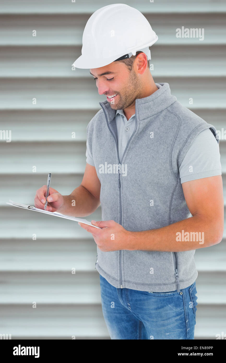 Composite image of smiling manual worker writing on clipboard Stock Photo