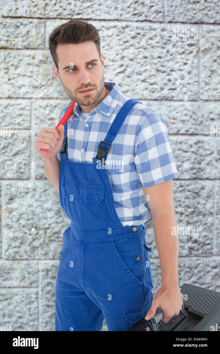 Composite image of repairman carrying toolbox while looking asway Stock Photo