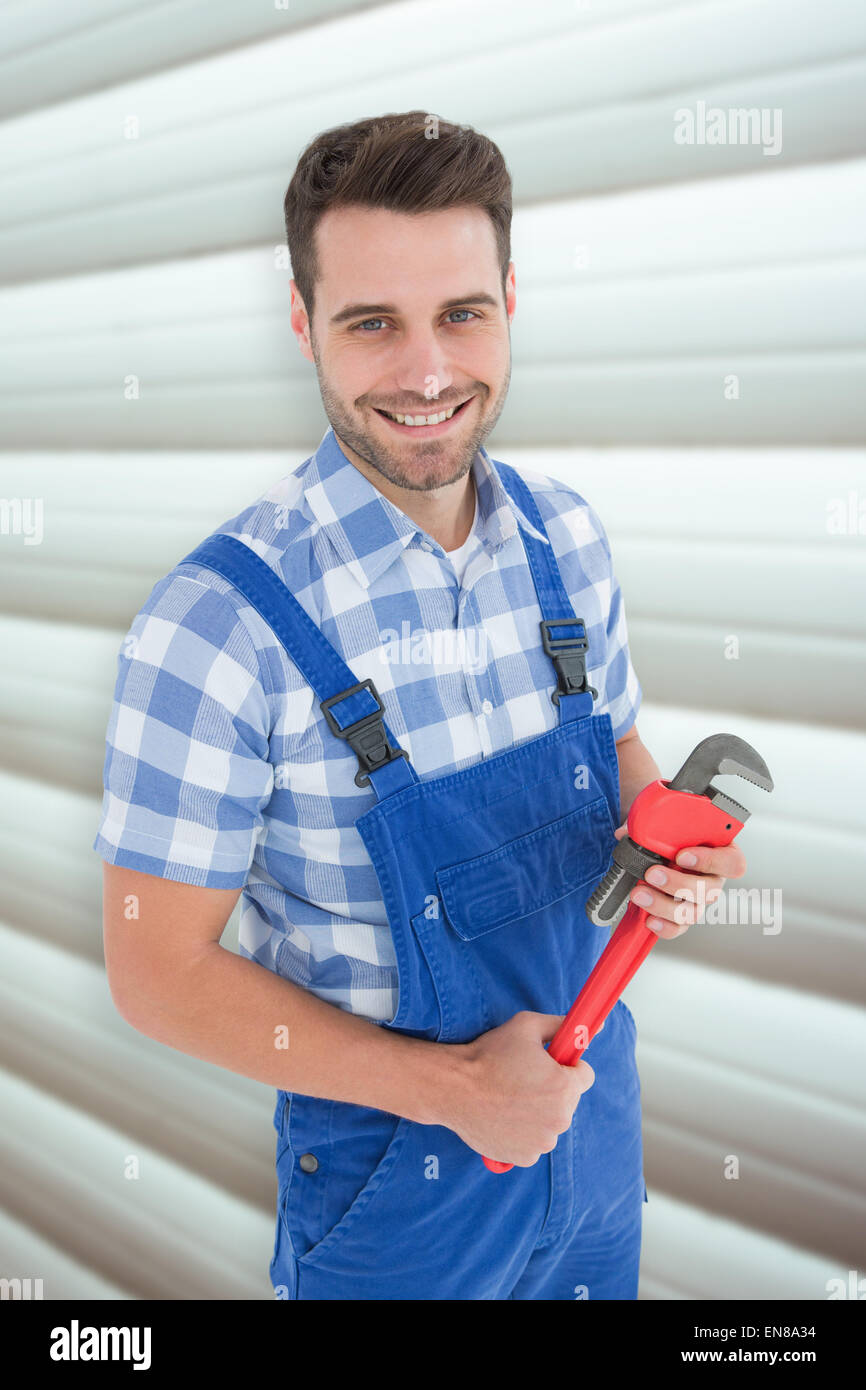Composite image of confident young male repairman holding monkey wrench Stock Photo