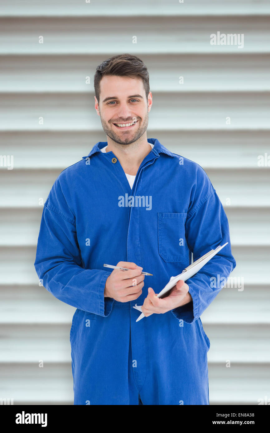 Composite image of smiling male mechanic writing on clipboard Stock Photo