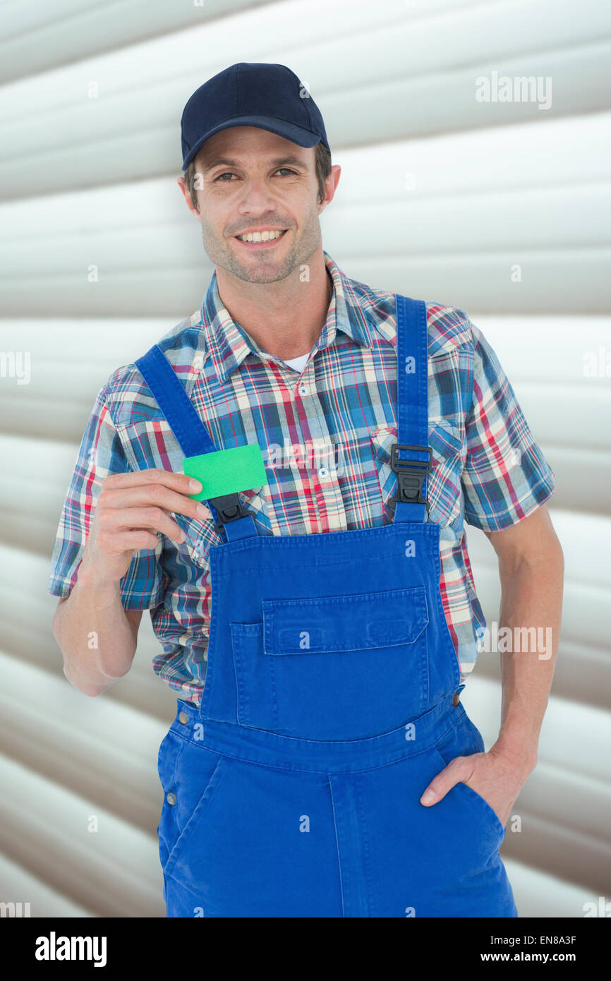 Composite image of confident plumber showing green card Stock Photo