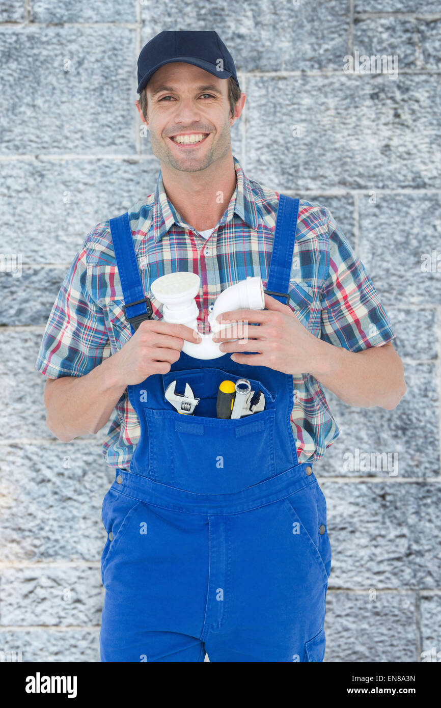 Composite image of confident plumber holding sink pipe Stock Photo