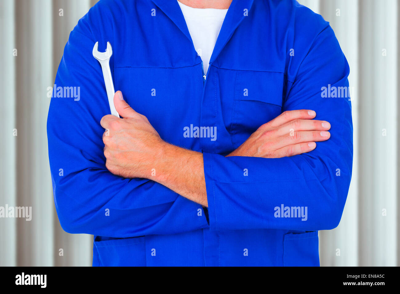 Composite image of male mechanic holding spanner on white background Stock Photo