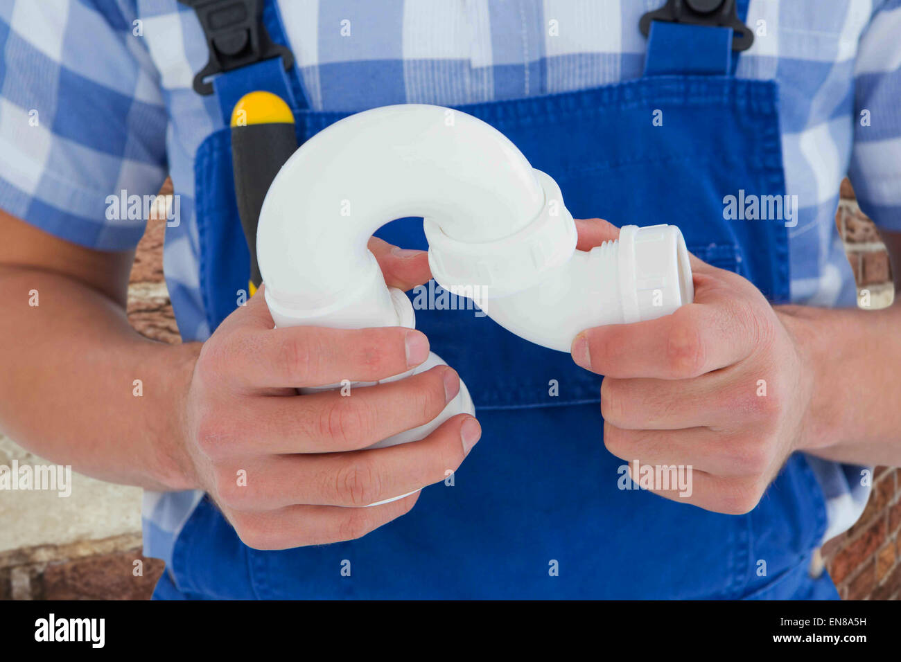 Composite image of plumber holding sink pipe on white background Stock Photo
