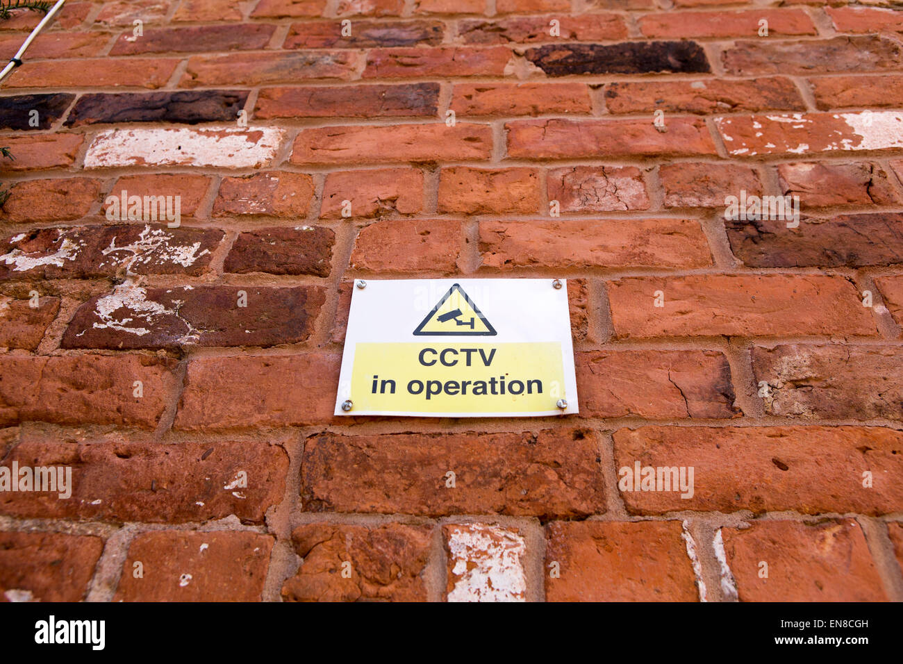 CCTV in operation sign on a red brick wall Stock Photo