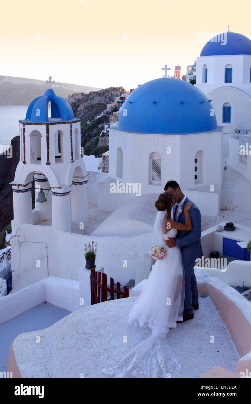 Newlyweds with traditional church in Oia, Santorini, Greece Stock Photo