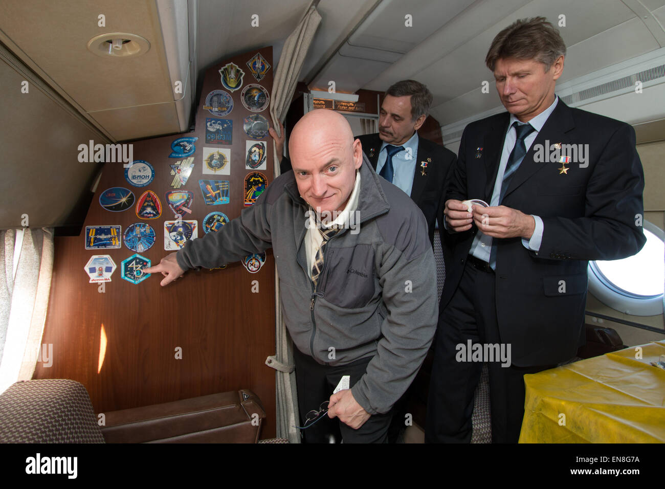 Expedition 43 NASA Astronaut Scott Kelly, points to his Expedition 43 crew mission patch after placing it on the  the Gagarin Cosmonaut Training Center (GCTC) aircraft during his flight from Star City, Russia, to Baikonur, Kazakhstan, with fellow crew members, Russian Cosmonauts Mikhail Kornienko, center, and Gennady Padalka of the Russian Federal Space Agency (Roscosmos), Saturday, March 14, 2015. The trio are preparing for launch to the International Space Station in their Soyuz TMA-16M spacecraft from the Baikonur Cosmodrome in Kazakhstan March 28, Kazakh time. As the one-year crew, Kelly a Stock Photo