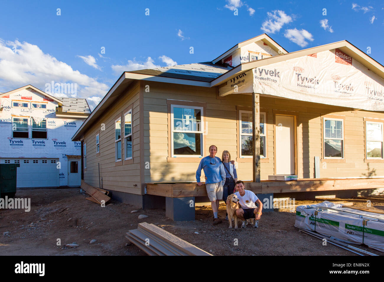 Family standing proudly in front of their new home under construction Stock Photo