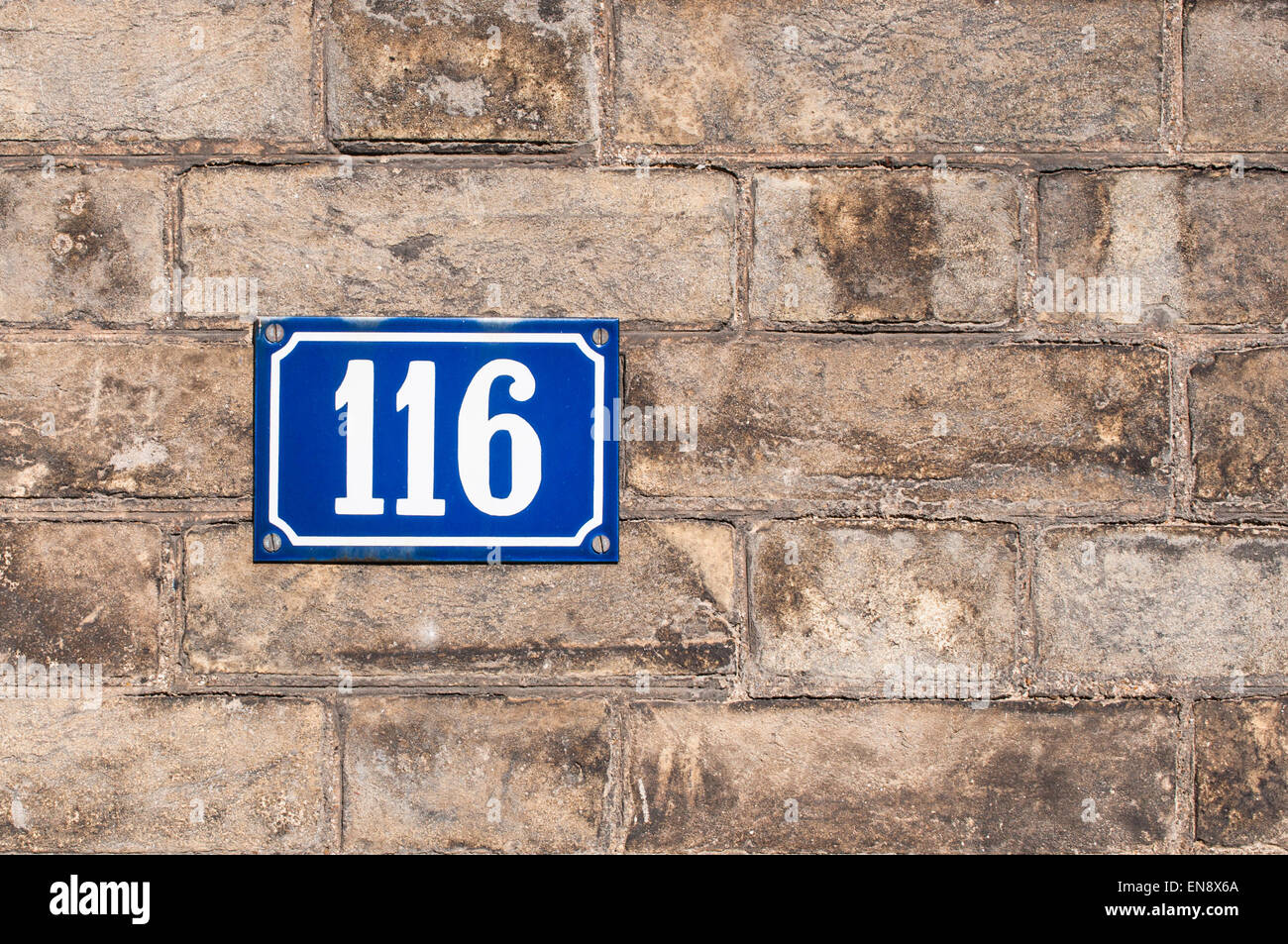 House number one hundred and sixteen painted on metal plate on brick wall Stock Photo