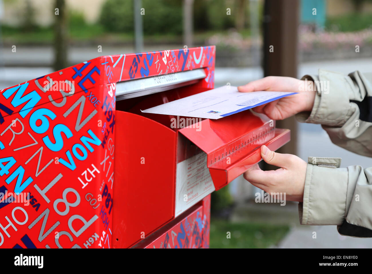 Hand sending a tax report letter in a red mail box Stock Photo