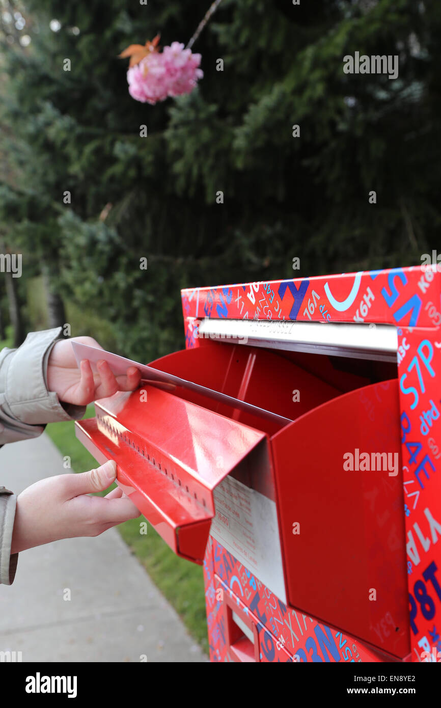 Hand sending a tax report letter in a red mail box Stock Photo