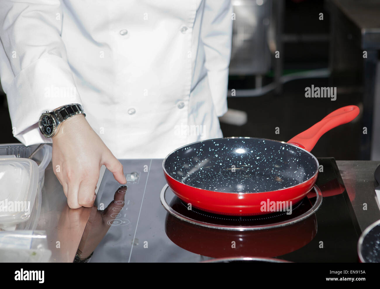 A woman hand turn the fire on just before cooking with a red pan Stock Photo