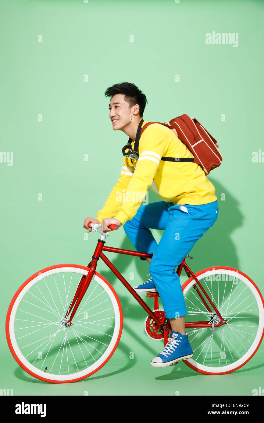 The stylish young man riding a bicycle Stock Photo