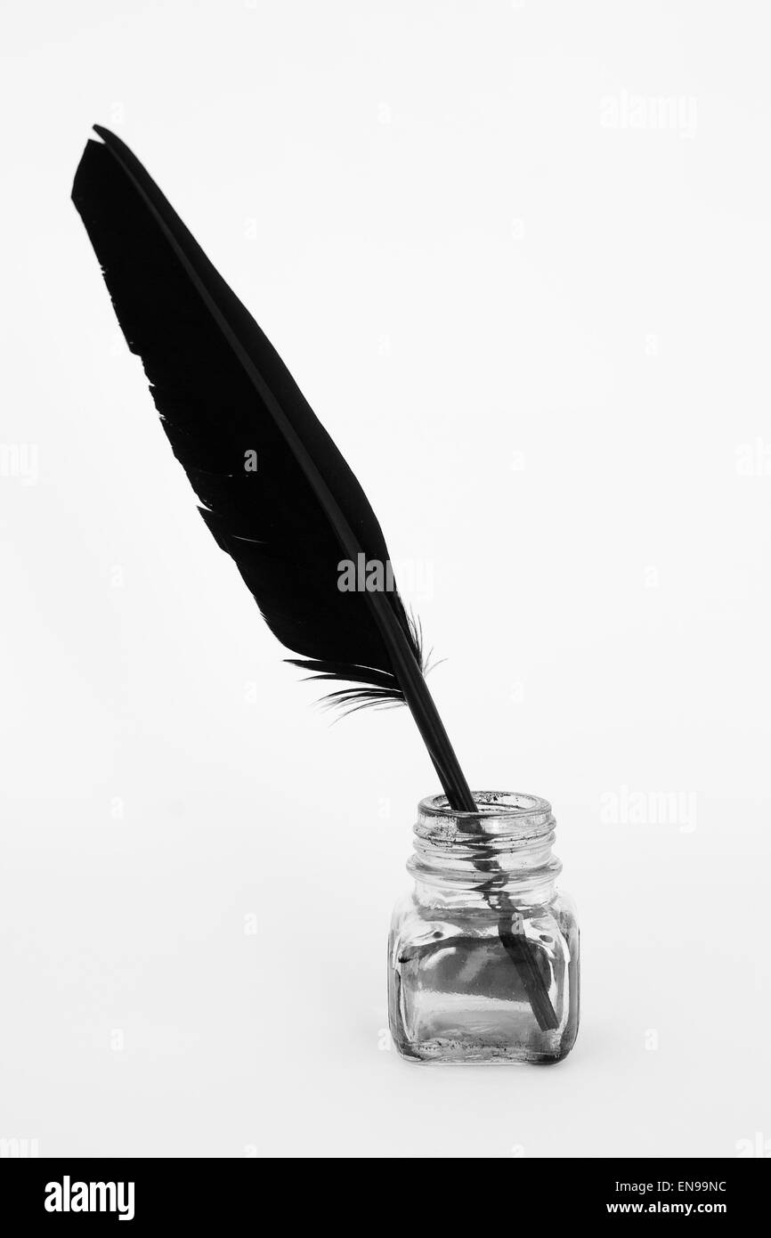 Black feather on white background and ink pot Stock Photo