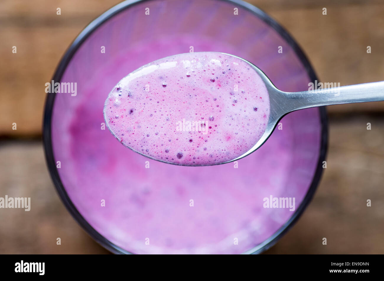 Spoon with berry smoothies on the background of a glass of cocktail Stock Photo