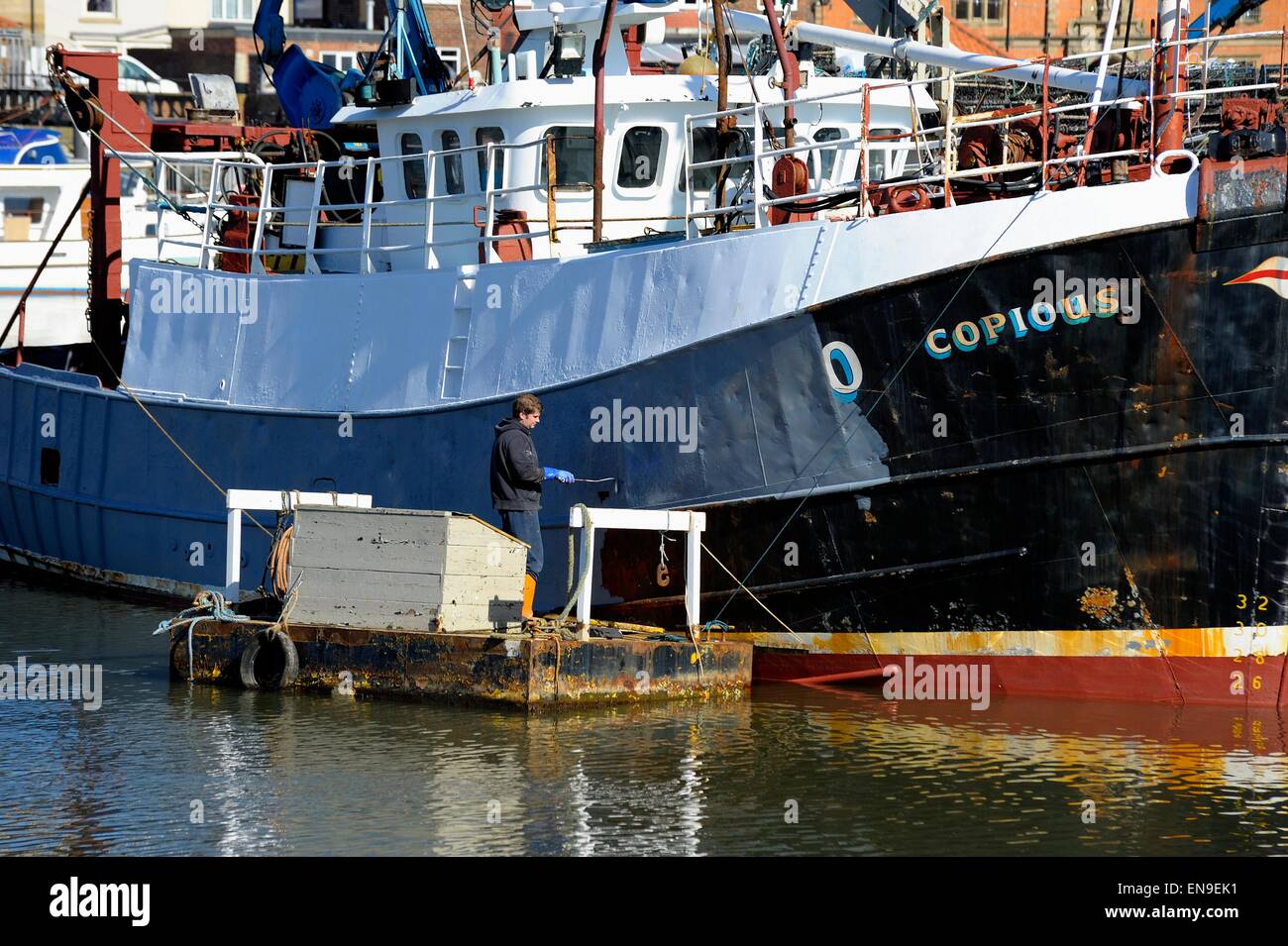 A man painting a fishing trawler needing copious amounts of paint. Stock Photo