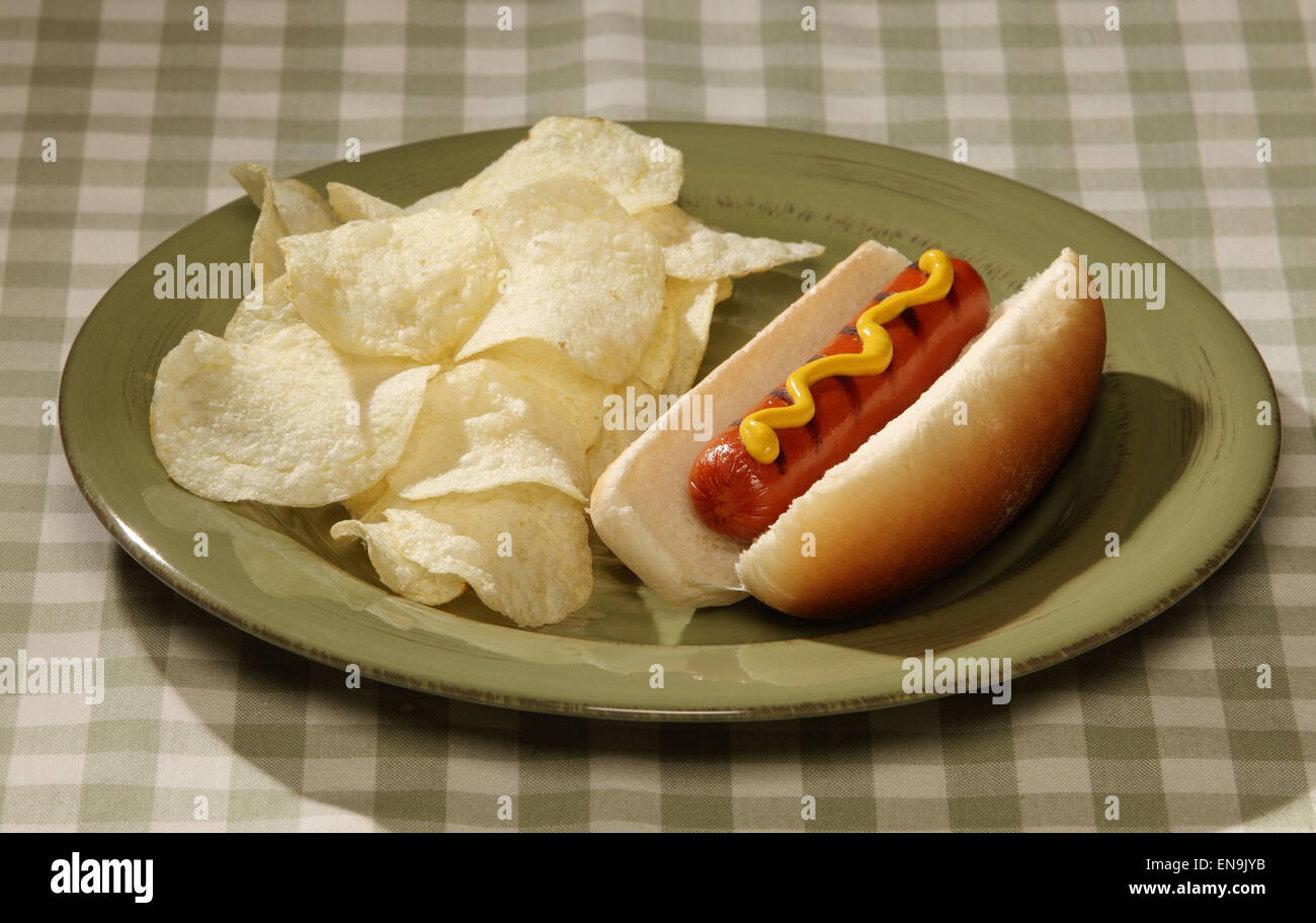 A hot dog on a plate with potato chips Stock Photo