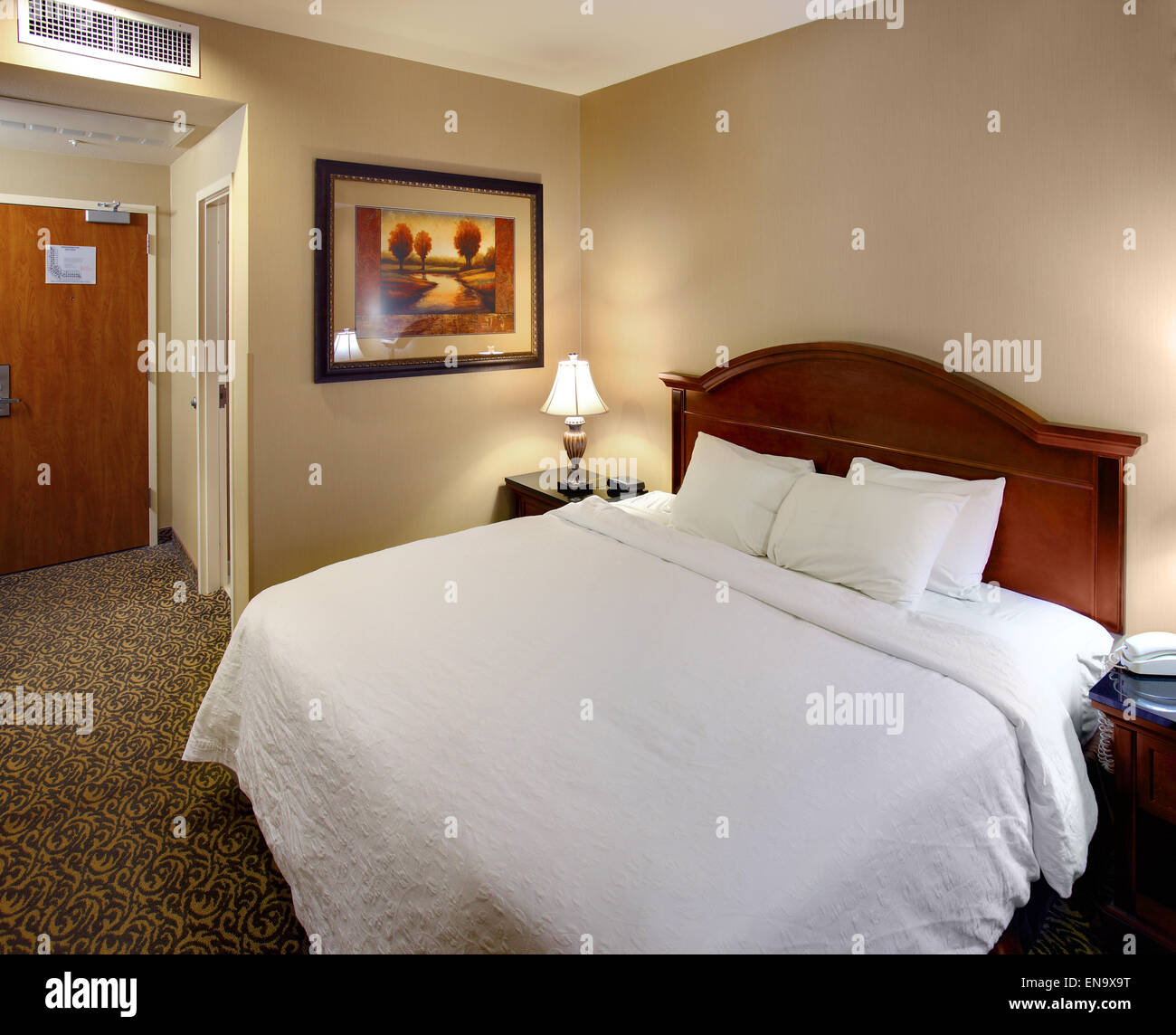 The interior of a mid-scale hotel suite, with a queen bed. Stock Photo
