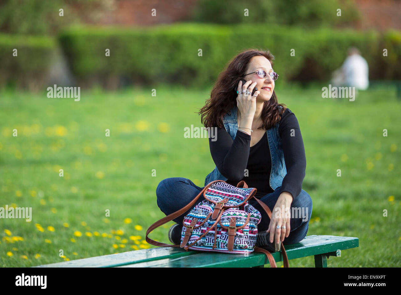 Woman sitting on a Park bench and talking on the phone Stock Photo - Alamy