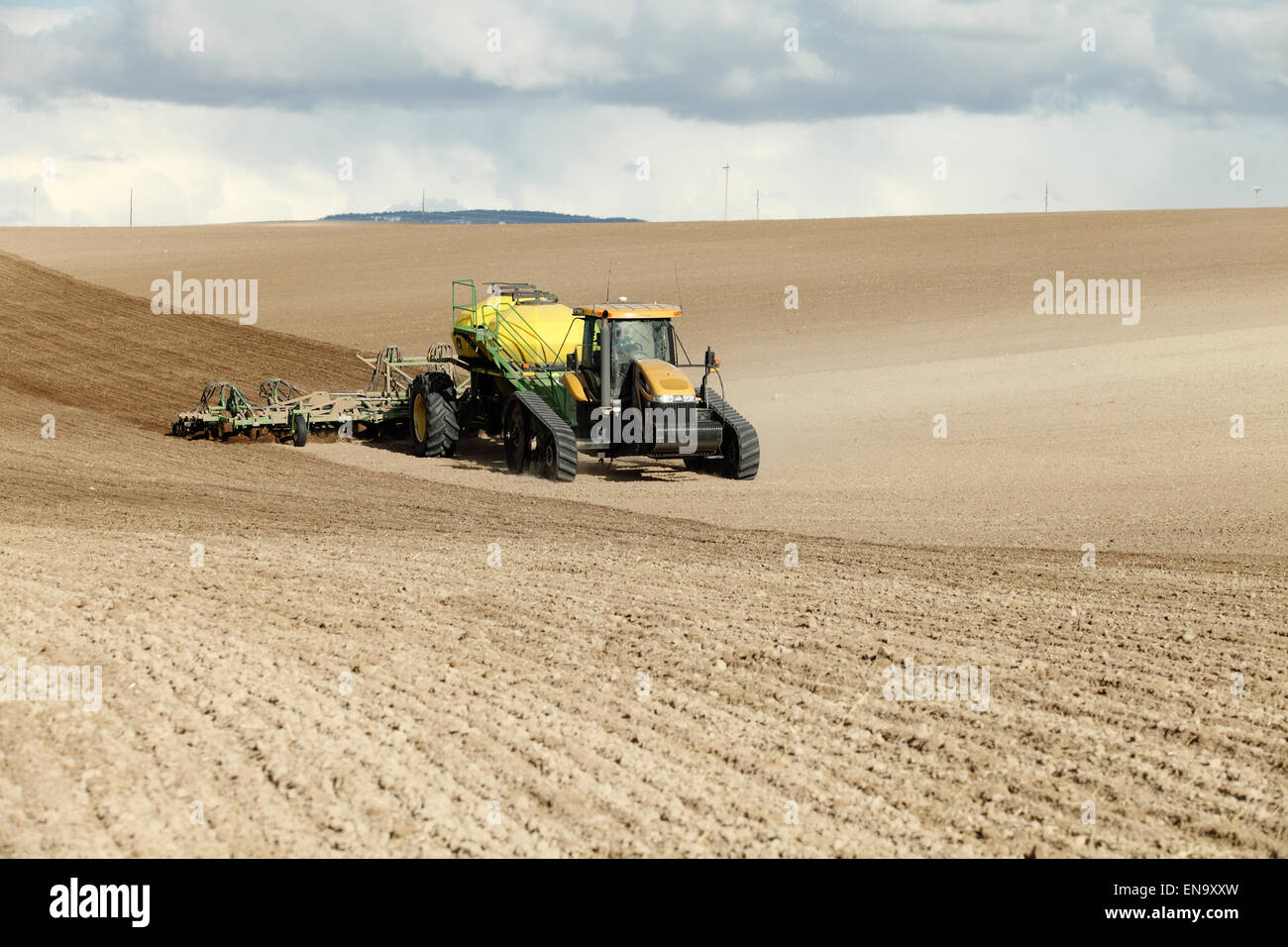 Farm machinery planting rows of wheat on a spring day in the fertile farm fields of Idaho. Stock Photo
