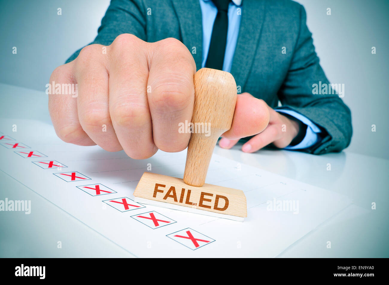 a young caucasian man at his office desk with a rubber stamp with the word failed Stock Photo