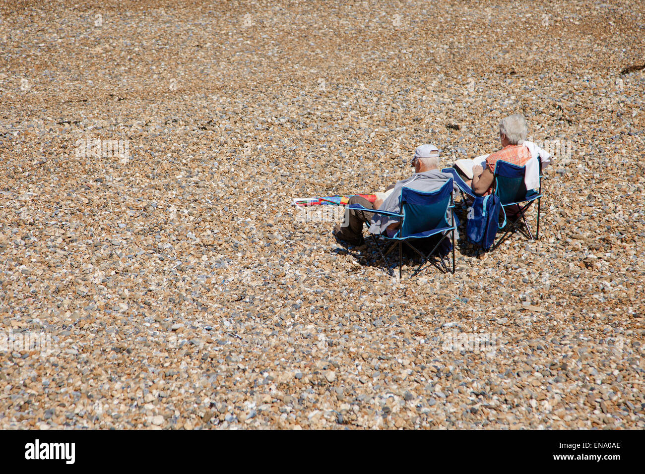 Elderly couple relaxing in chairs on a shingle beach look out to sea Stock Photo
