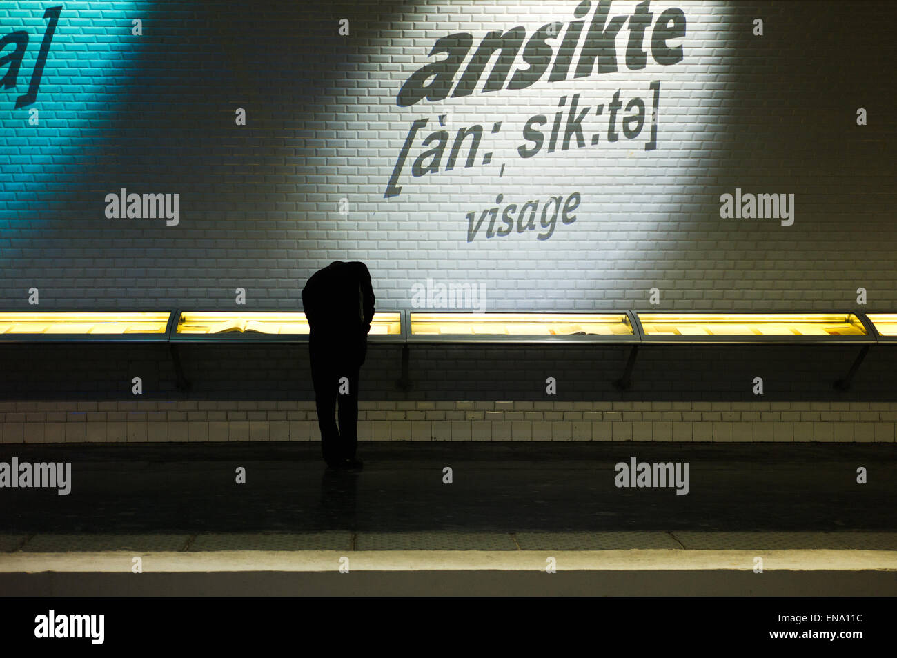 Silhouette of man leaning down to watch something in a subway art exhibit (where the head is not shown). Stock Photo