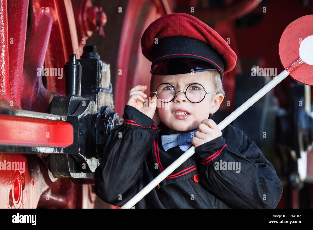 Portrait of a cute little child boy with annoyed facial expression as nostalgic railway conductor in vintage costume Stock Photo
