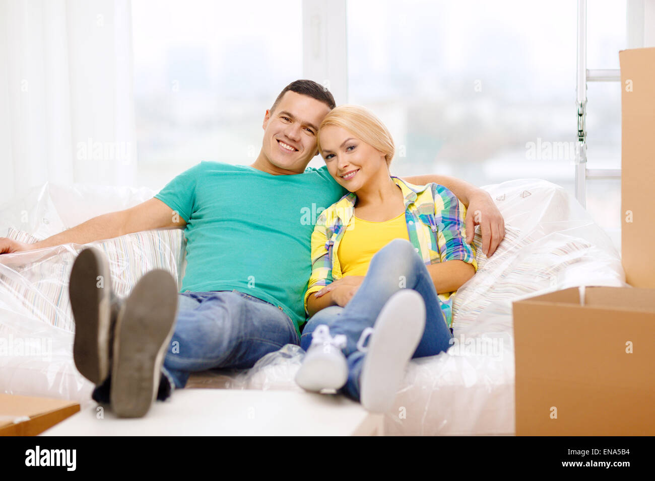 smiling couple relaxing on sofa in new home Stock Photo - Alamy