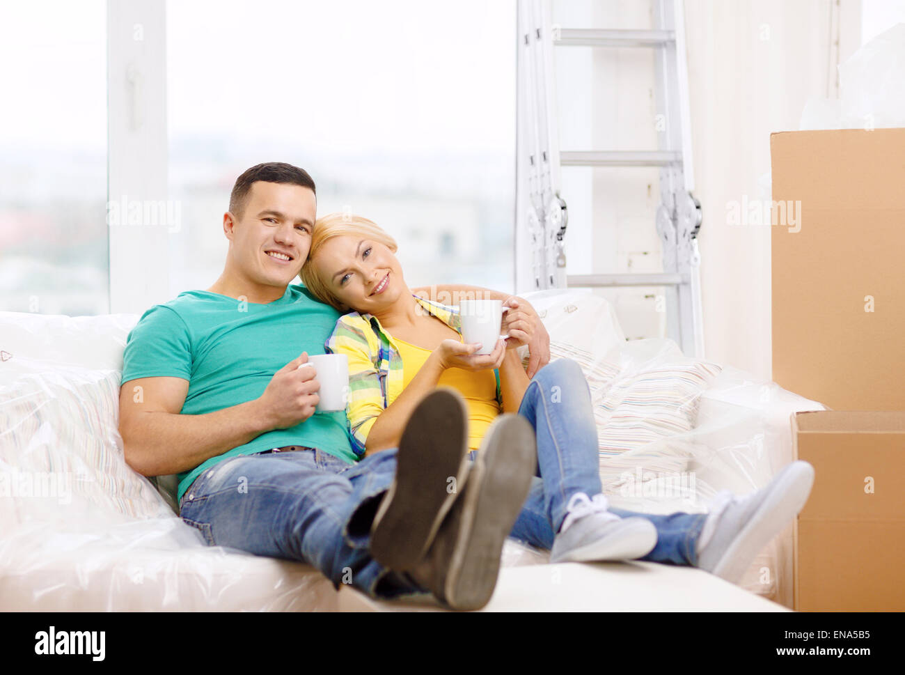 smiling couple relaxing on sofa in new home Stock Photo - Alamy