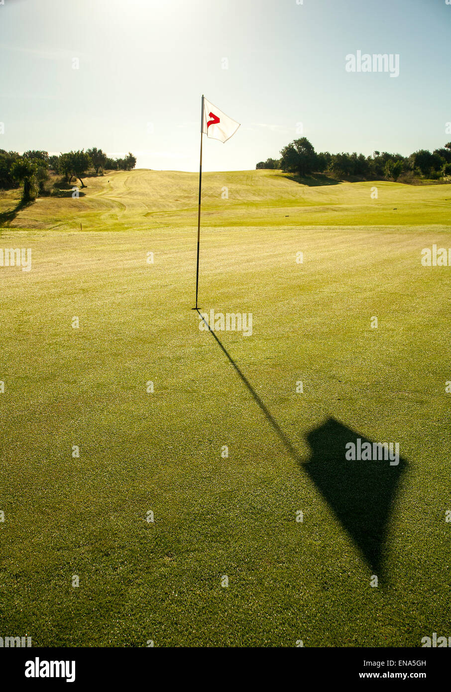 Golf flag in full sun on Green, long shadow. Stock Photo