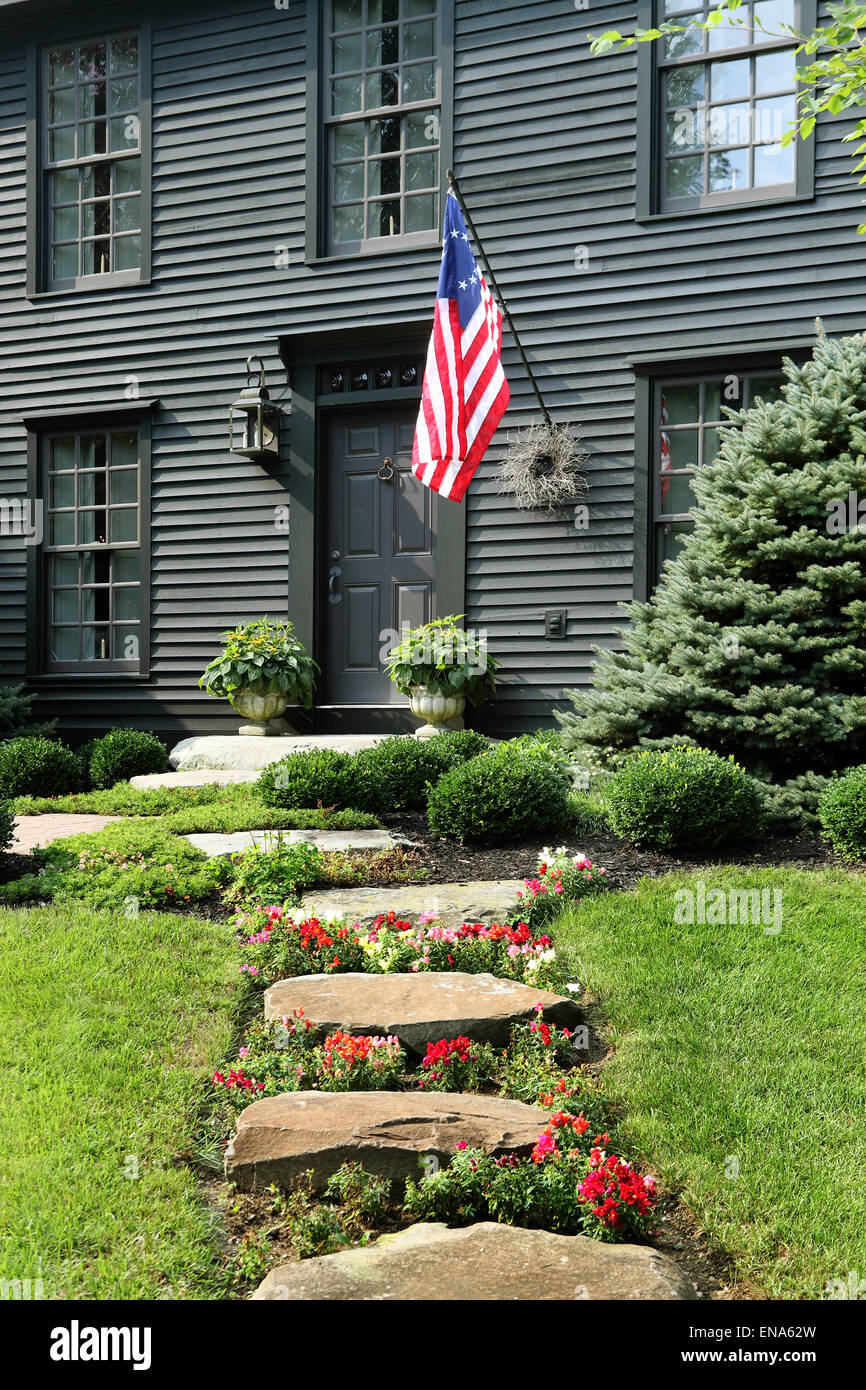 An image of the exterior and landscaping at a primitive colonial salt box style reproduction home. Stock Photo