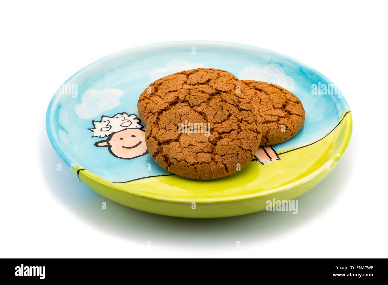There is a smiling sheep underneath the cookies on a colorful plate. Image is isolated on a white background. Stock Photo