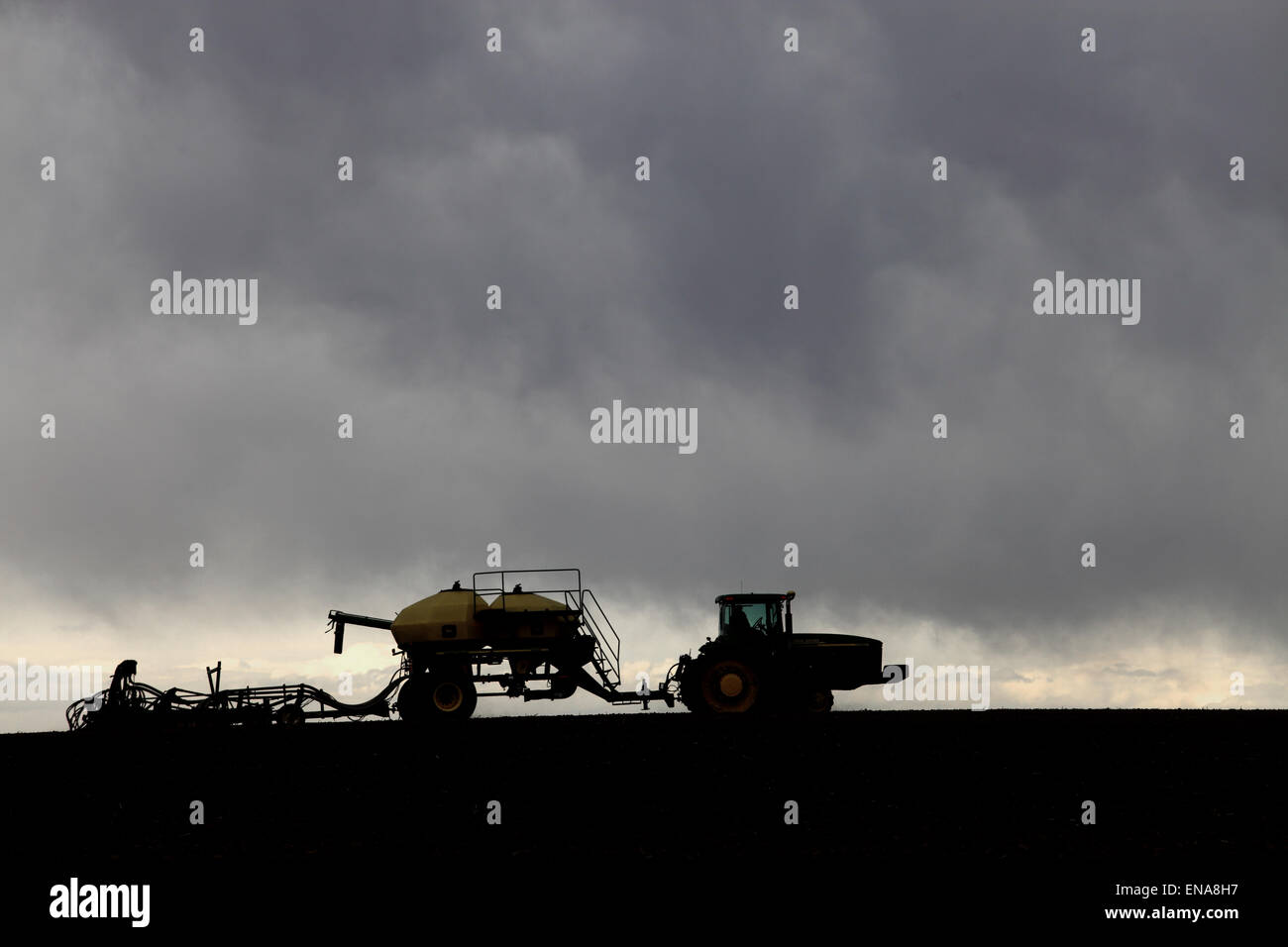 A tractor pulling agricultural implements, planting wheat in the fertile farm fields of Idaho.. Stock Photo