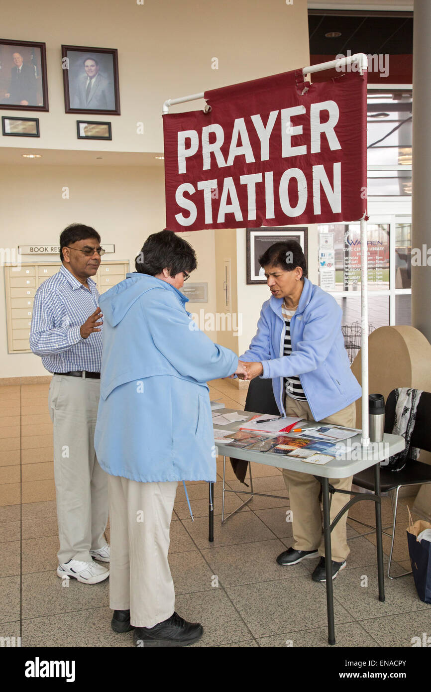 Warren, Michigan USA - Christian activists pray with a woman at their 'prayer station' in the lobby of city hall. A few steps away, atheists staff a 'reason station.' Originally, the city allowed only the prayer station. It took a federal court's order to allow the atheists to set up their table. Credit:  Jim West/Alamy Live News Stock Photo