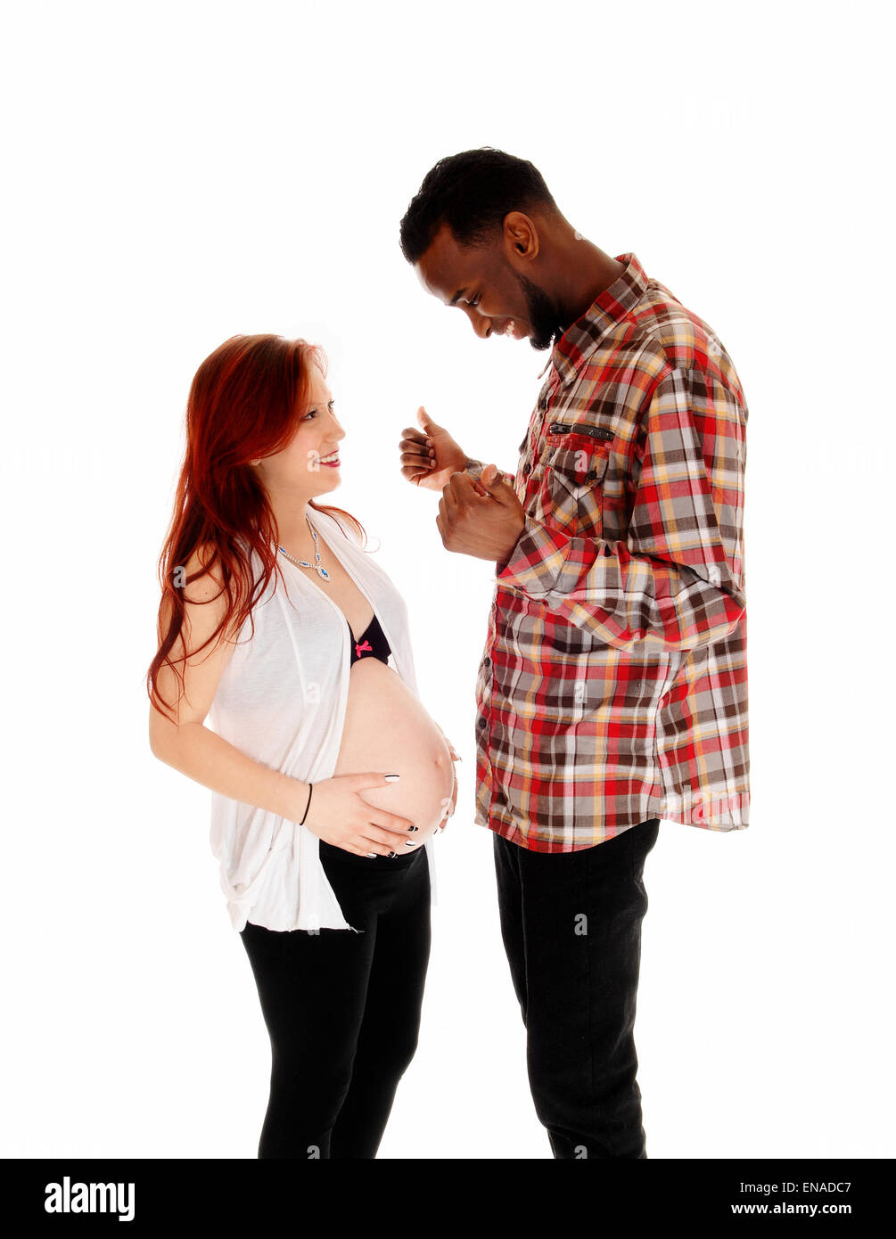 A young pregnant couple standing isolated for white background, the African America man with his thump's up. Stock Photo