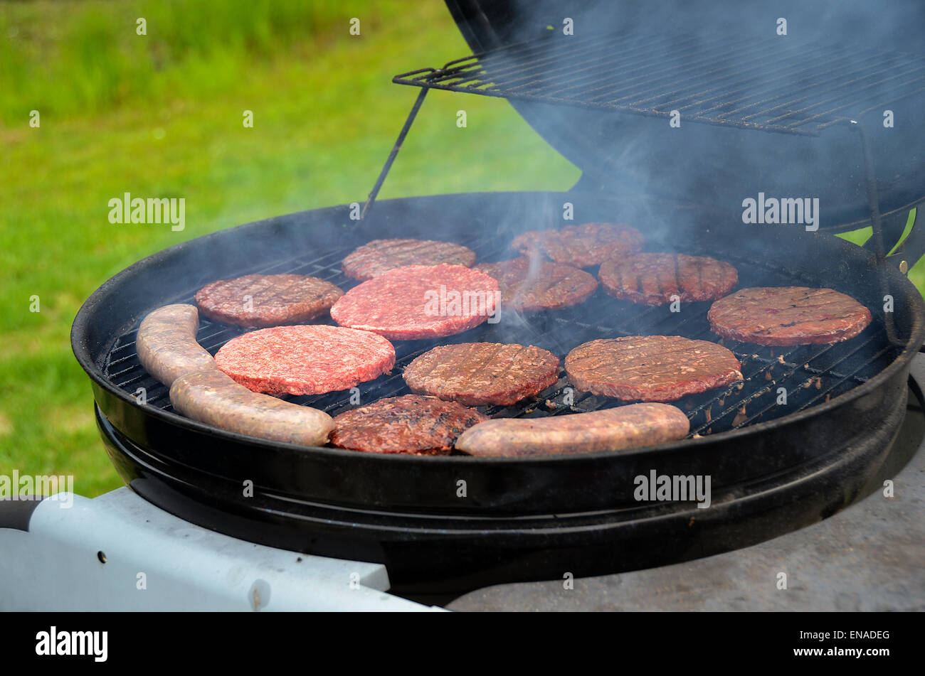 Hamburg patties and bratwursts cooking on a barbecue grill. Stock Photo