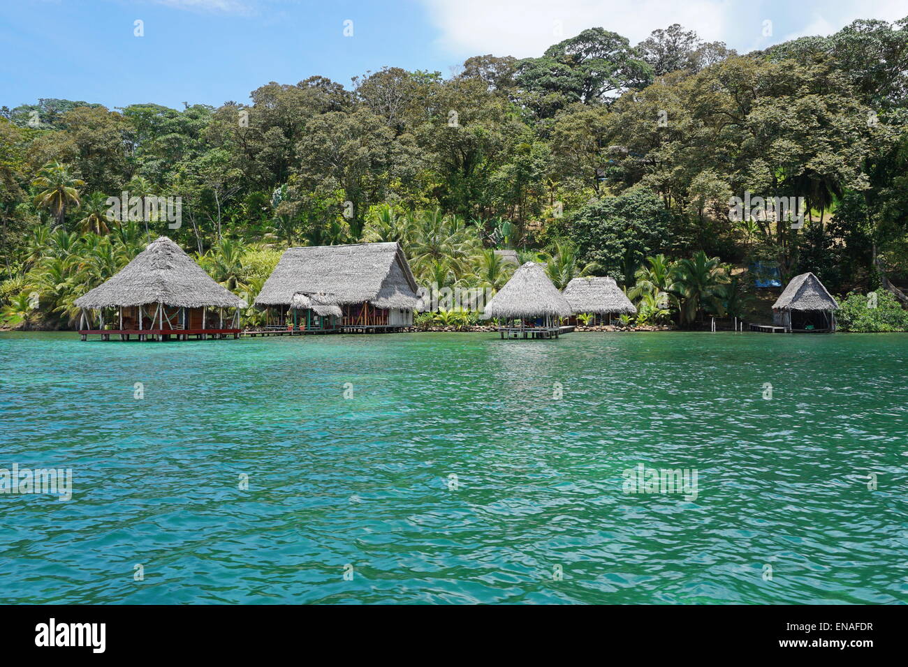 Tropical eco lodge with thatch huts over the sea and lush vegetation, Caribbean shore of Panama, Central America Stock Photo