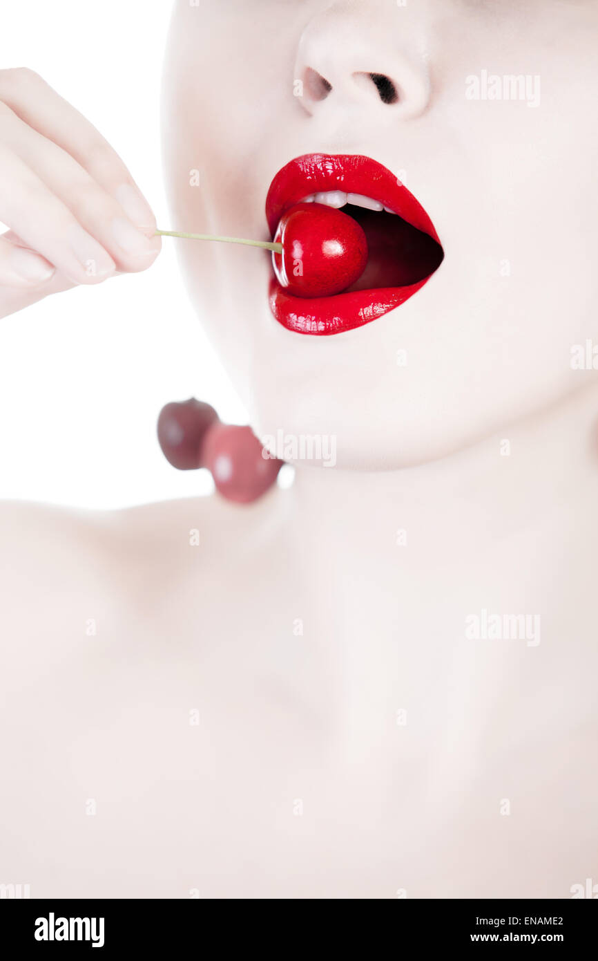 Concept of white woman eating cherry. Close up fashion shooting. Red cherry on a white woman`s mouth. Studio shooting Stock Photo