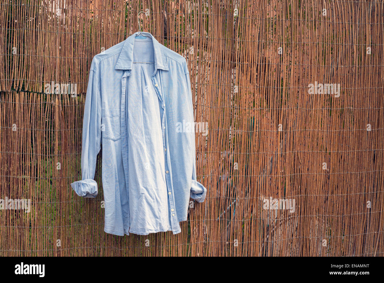 Blue shirt hanging on wicker wall Stock Photo