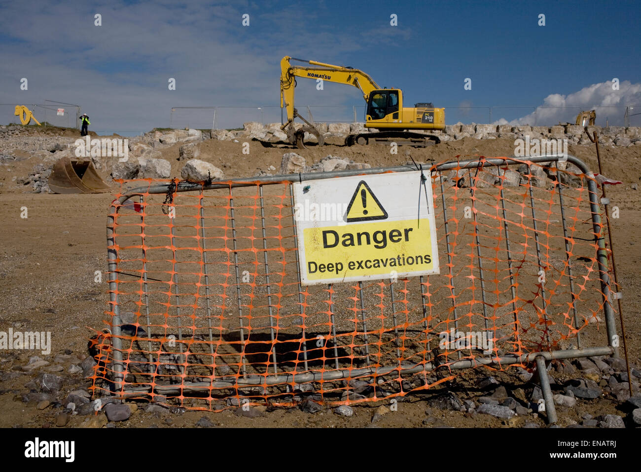 notice of komatsu digger in action lifting boulders to strengthen protection of Newton beach Stock Photo