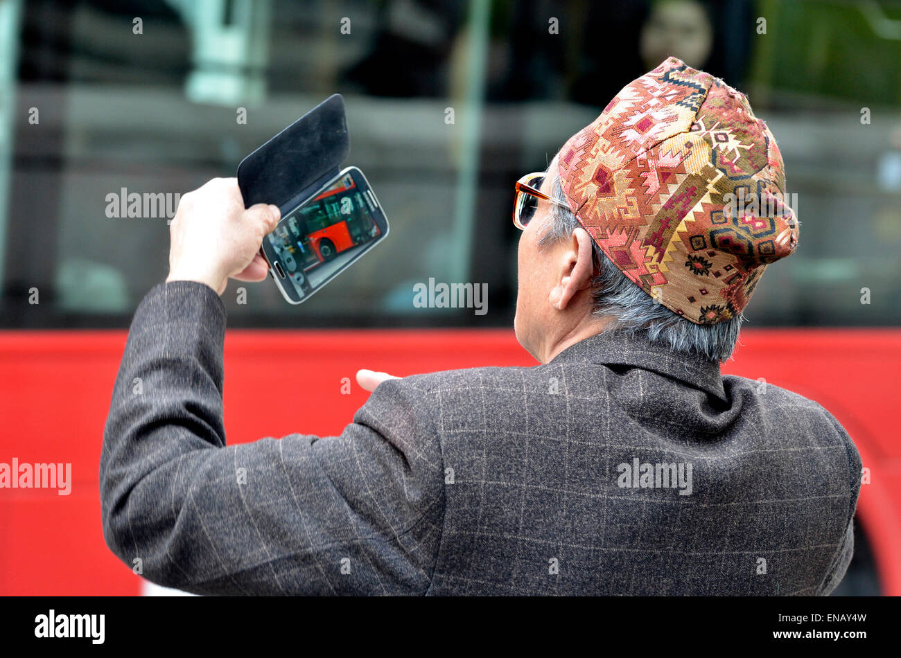 London, England, UK. Old Nepalese man (retired Gurkha) taking a photo on his mobile phone Stock Photo