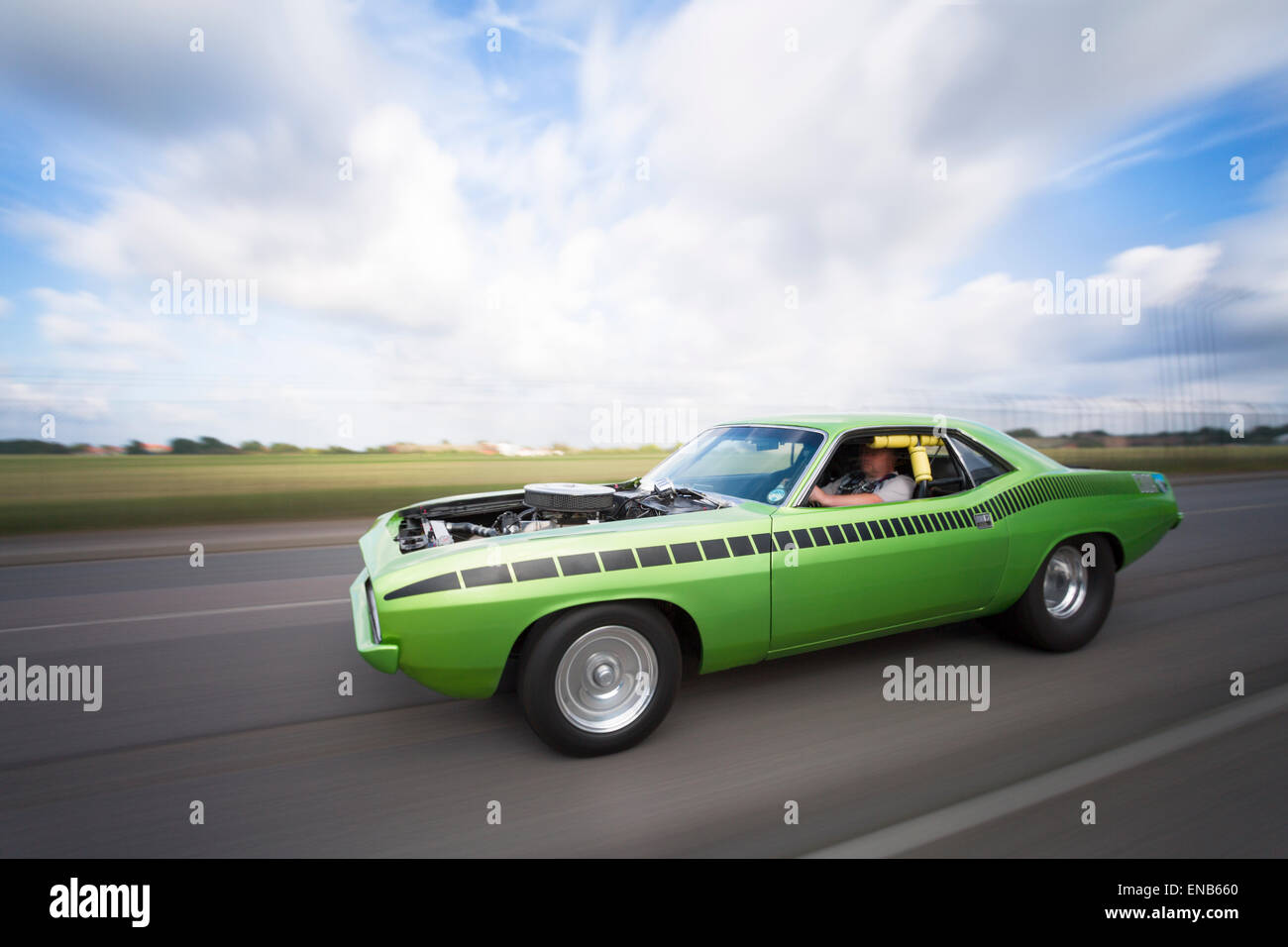 Plymouth Barracuda in an urban location moving, panned, rig shot with bonnet hood off. Stock Photo