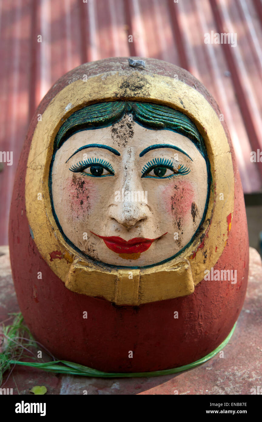 Close up detail of an red painted egg shaped stone statue of a spirit or Nat at the entrance to Mount Popa Myanmar Stock Photo