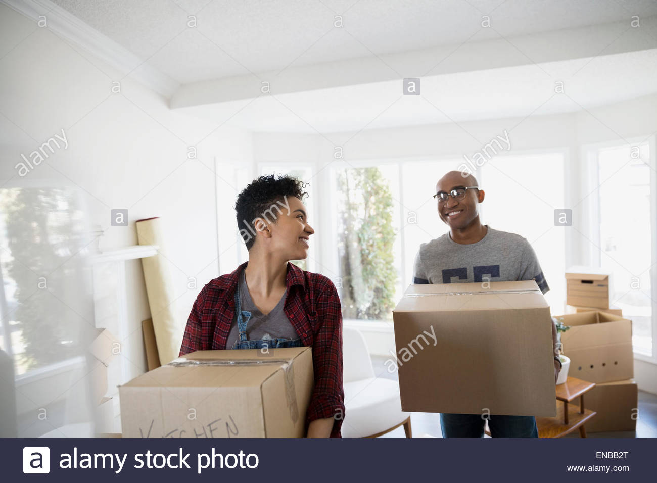 Couple carrying moving boxes in living room Stock Photo